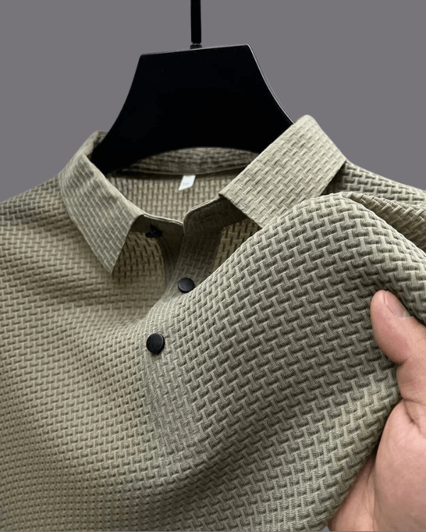 Green textured shirt on a mannequin with a hand holding it, against a gray background