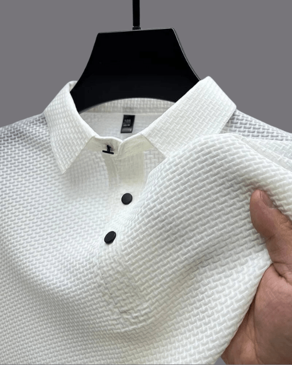 White textured shirt on a hanger with a hand holding it against a gray background