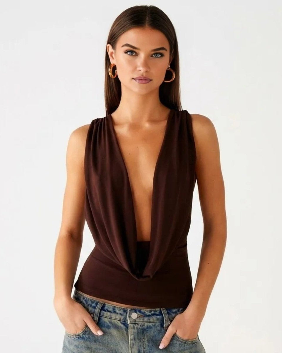 Model wearing the Rhea dark brown cowl neck top, featuring a deep plunging neckline and draped front, paired with jeans.