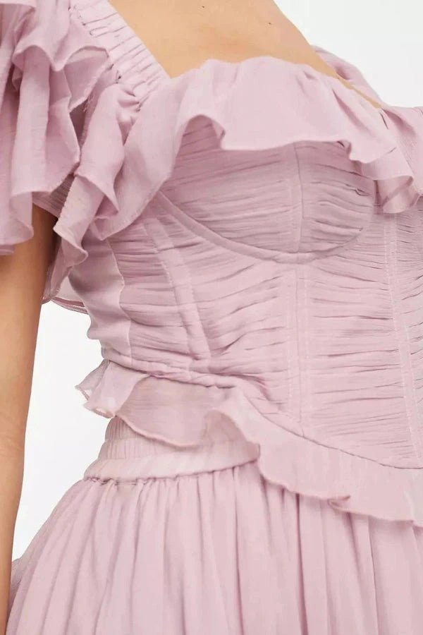 Model wearing fenloform Freyna dusty lilac two-piece ruffle dress with corset top and tiered midi skirt