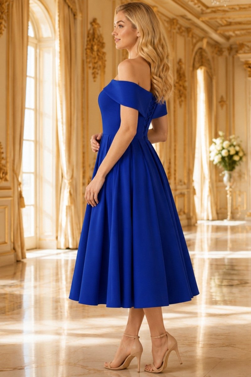 A woman modeling an off-the-shoulder royal blue midi dress in a grand, sunlit palace hallway with gold walls and columns.