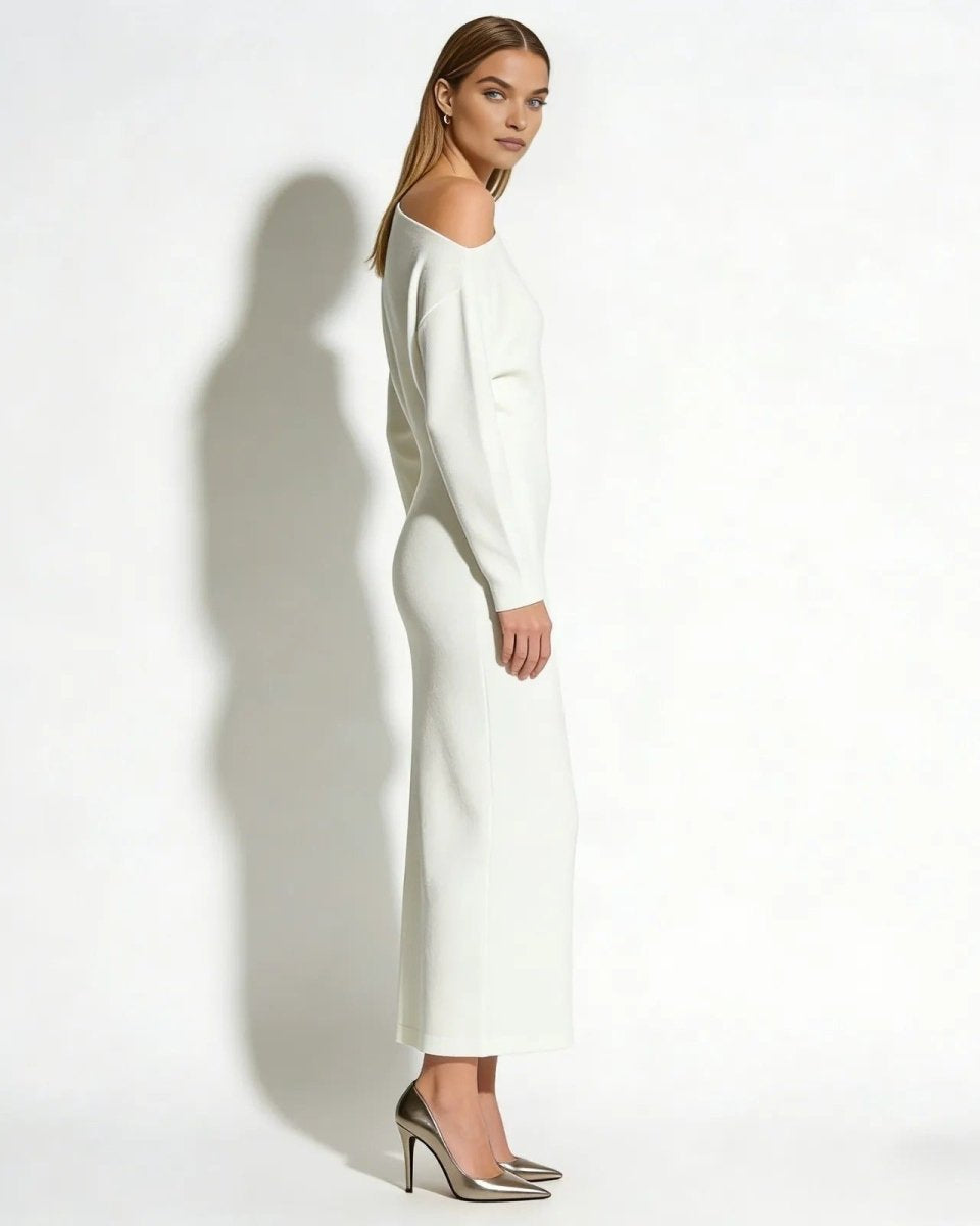 Side profile of a model wearing the Selena asymmetrical long sleeve selena knit dress with metallic heels.