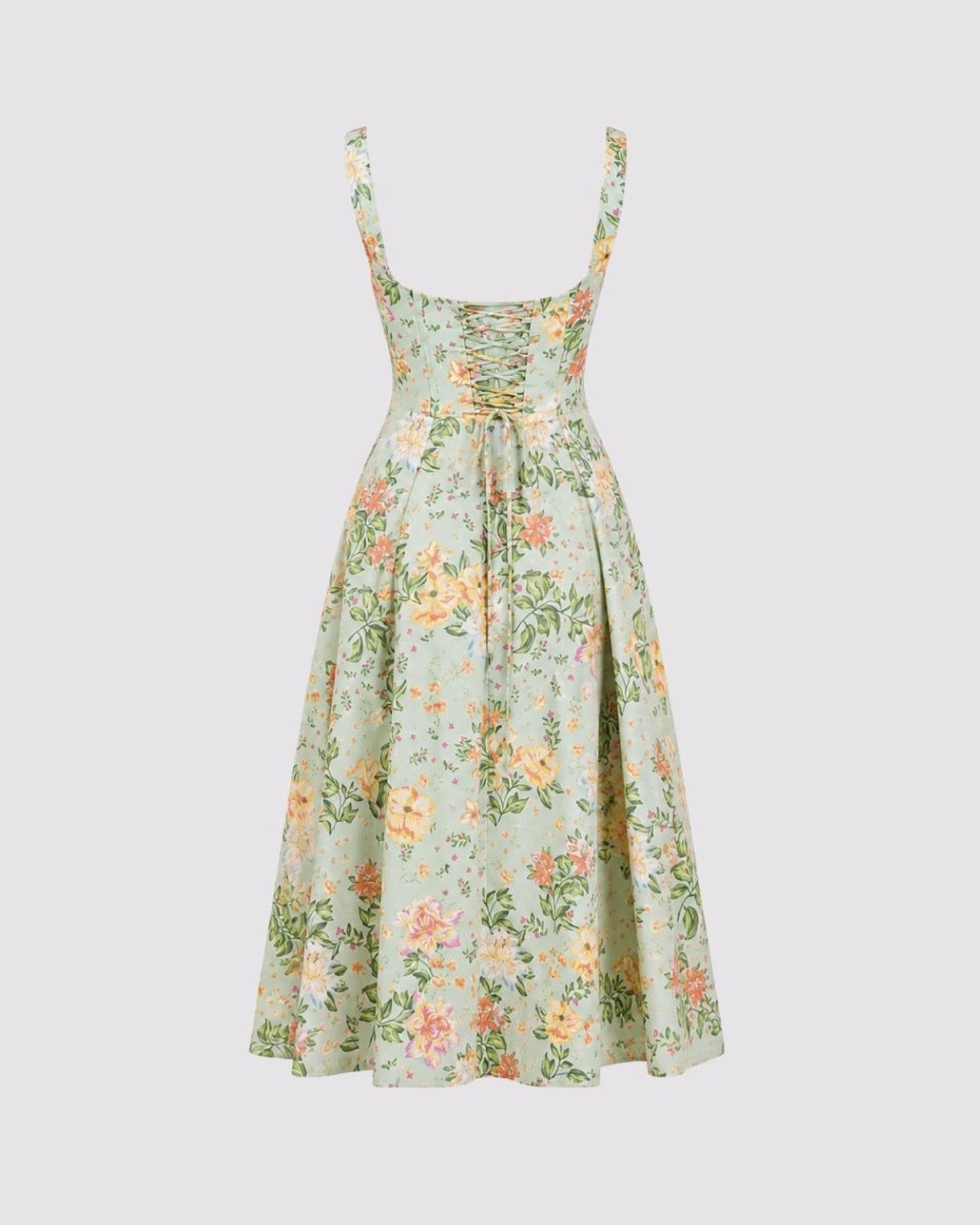A sleeveless midi dress with a light sage green base and a delicate multicolor floral print in yellow, orange, and pink, featuring thin shoulder straps and a gathered waist.