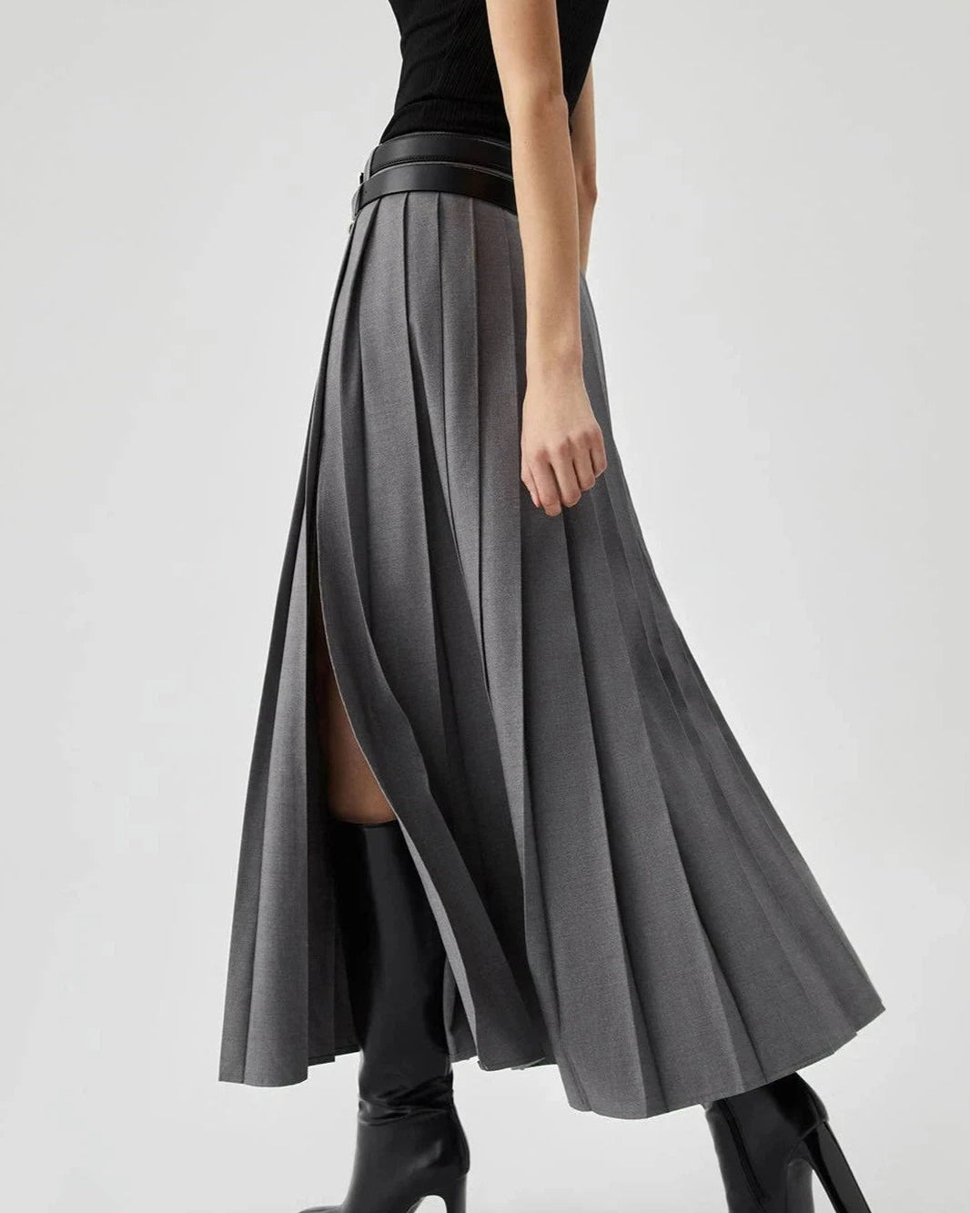Person wearing a black top and gray pleated skirt on a white background