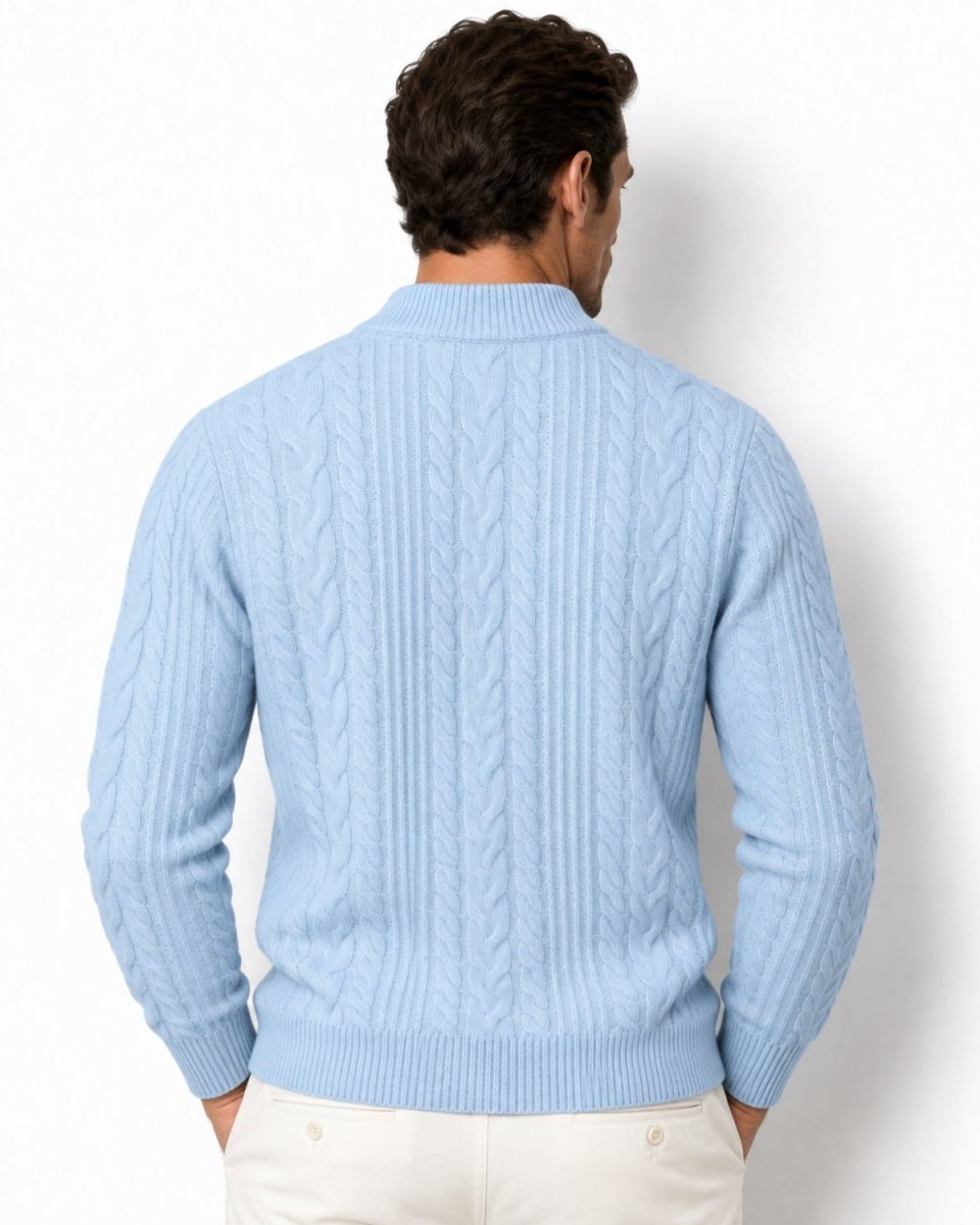 A man viewed from the back wearing a sky blue cable-knit sweater and cream pants against a plain white background.