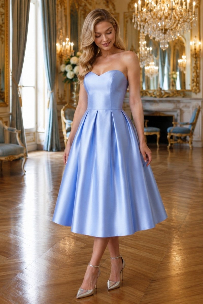 A woman models a strapless light blue satin A-line midi dress in an elegant, opulent room with gold chandeliers and parquet flooring.