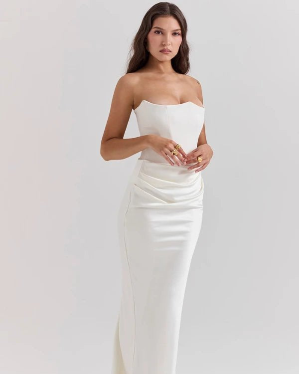 Woman wearing a strapless white evening gown on a plain background