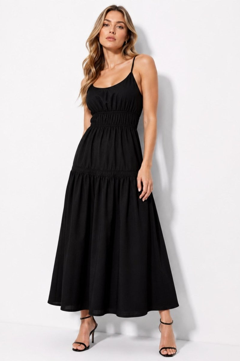 Woman wearing a sophisticated black smocked waist tiered maxi dress