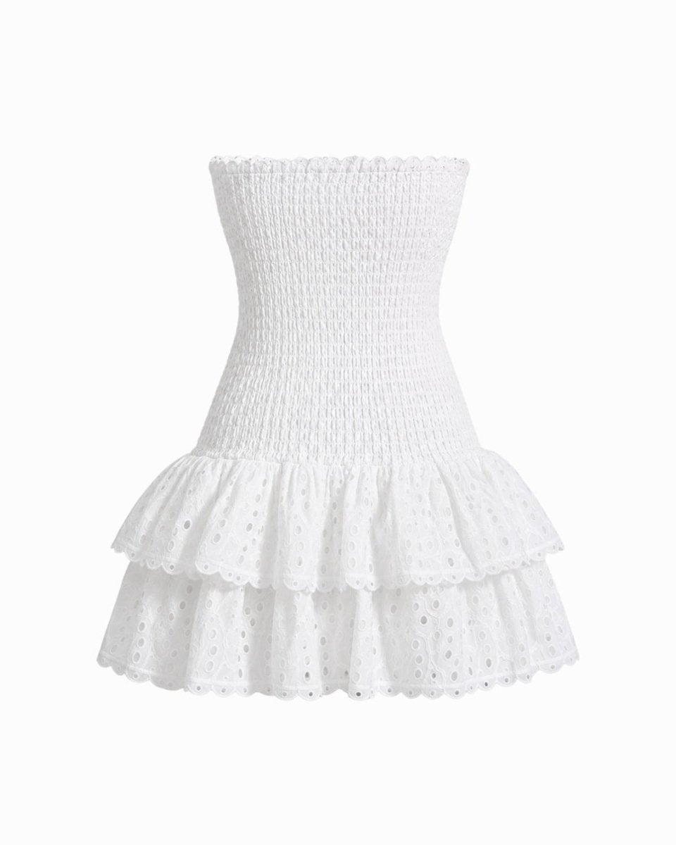 White strapless smocked eyelet mini dress with a ruffled tiered skirt, shown against a plain white background.