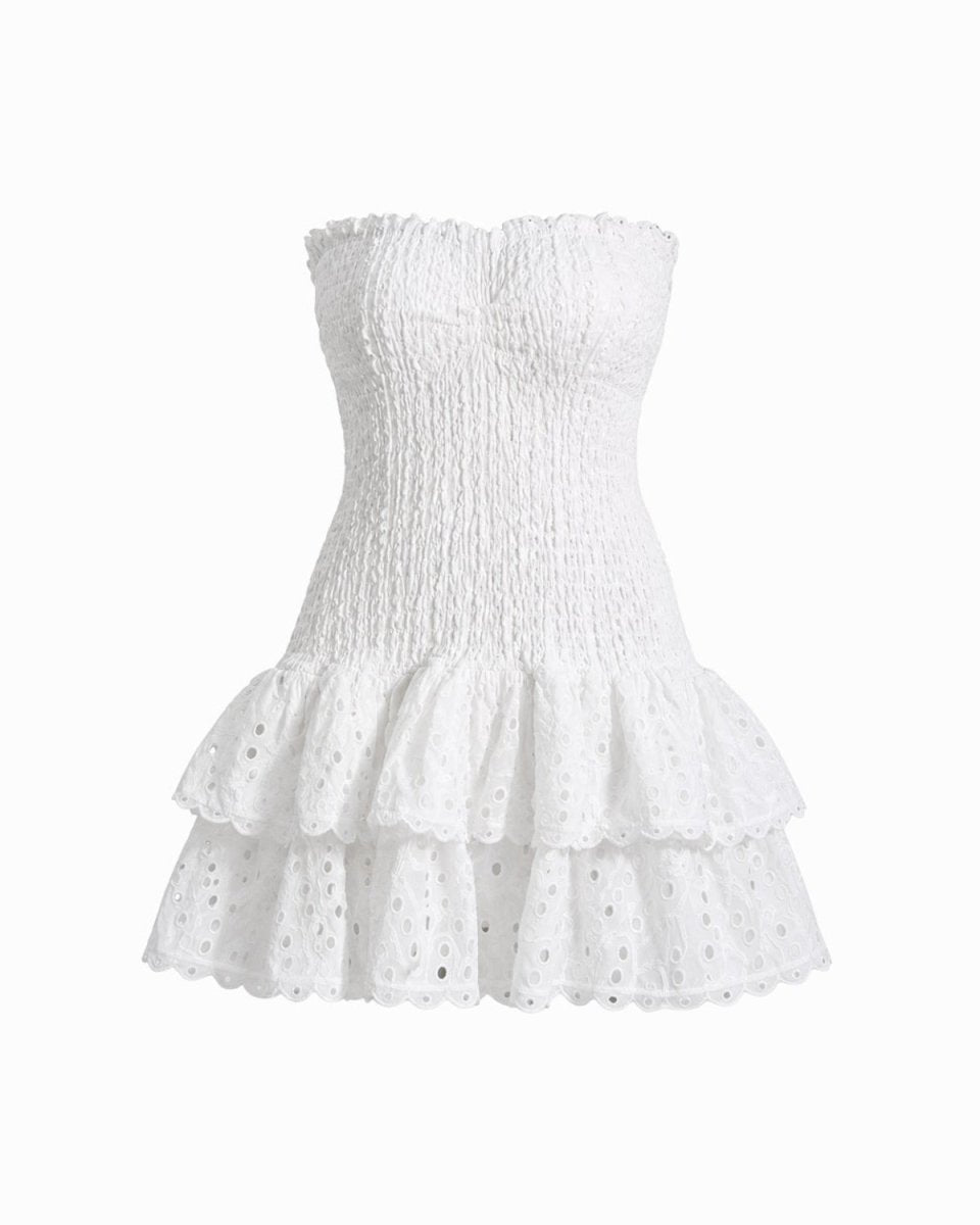 A white strapless eyelet mini dress with a smocked bodice and tiered ruffle skirt, shown against a plain white background.