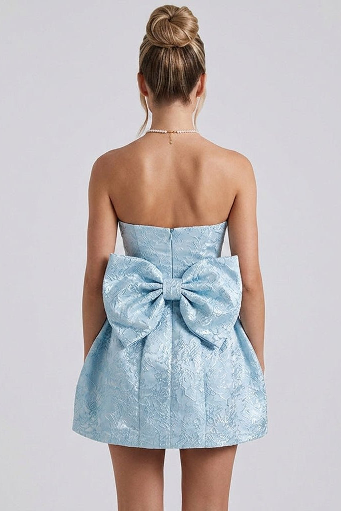 Back view of the light blue cocktail dress showcasing the dramatic oversized statement bow and concealed center zipper.