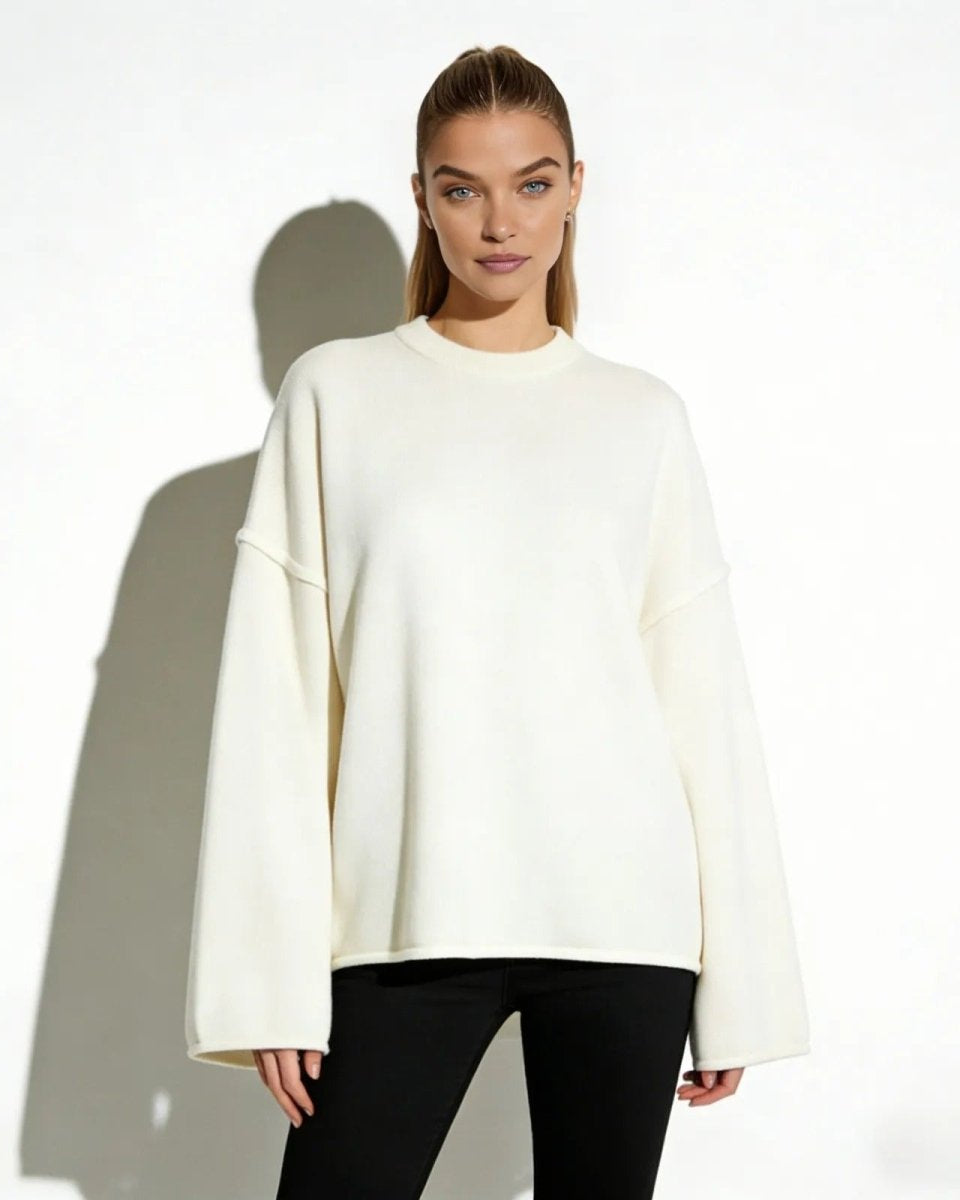 Model wearing the Krystal oversized cream sweater with a boxy fit and wide sleeves, styled with black pants against a white background.