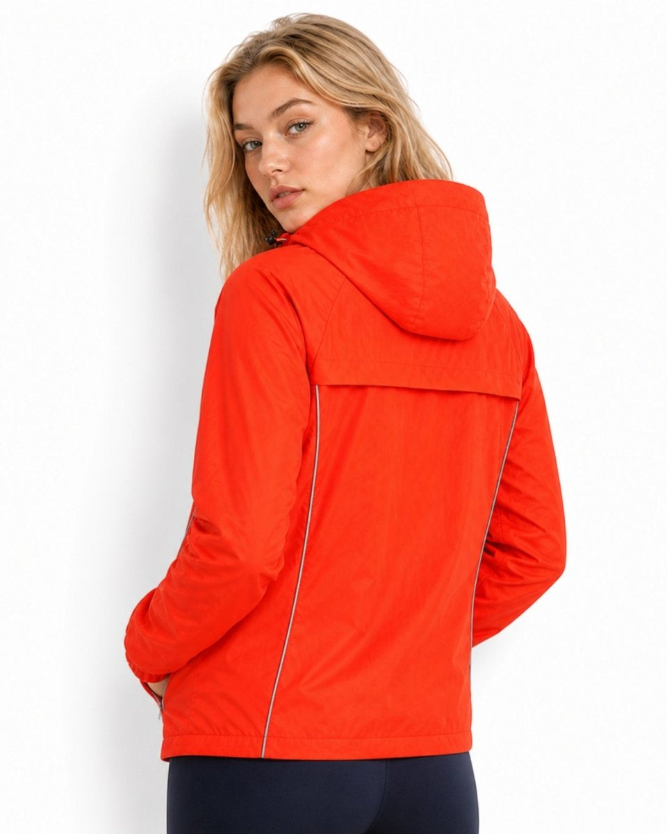 Back view of woman wearing bright orange hooded running jacket featuring a structured back yoke and reflective safety piping.
