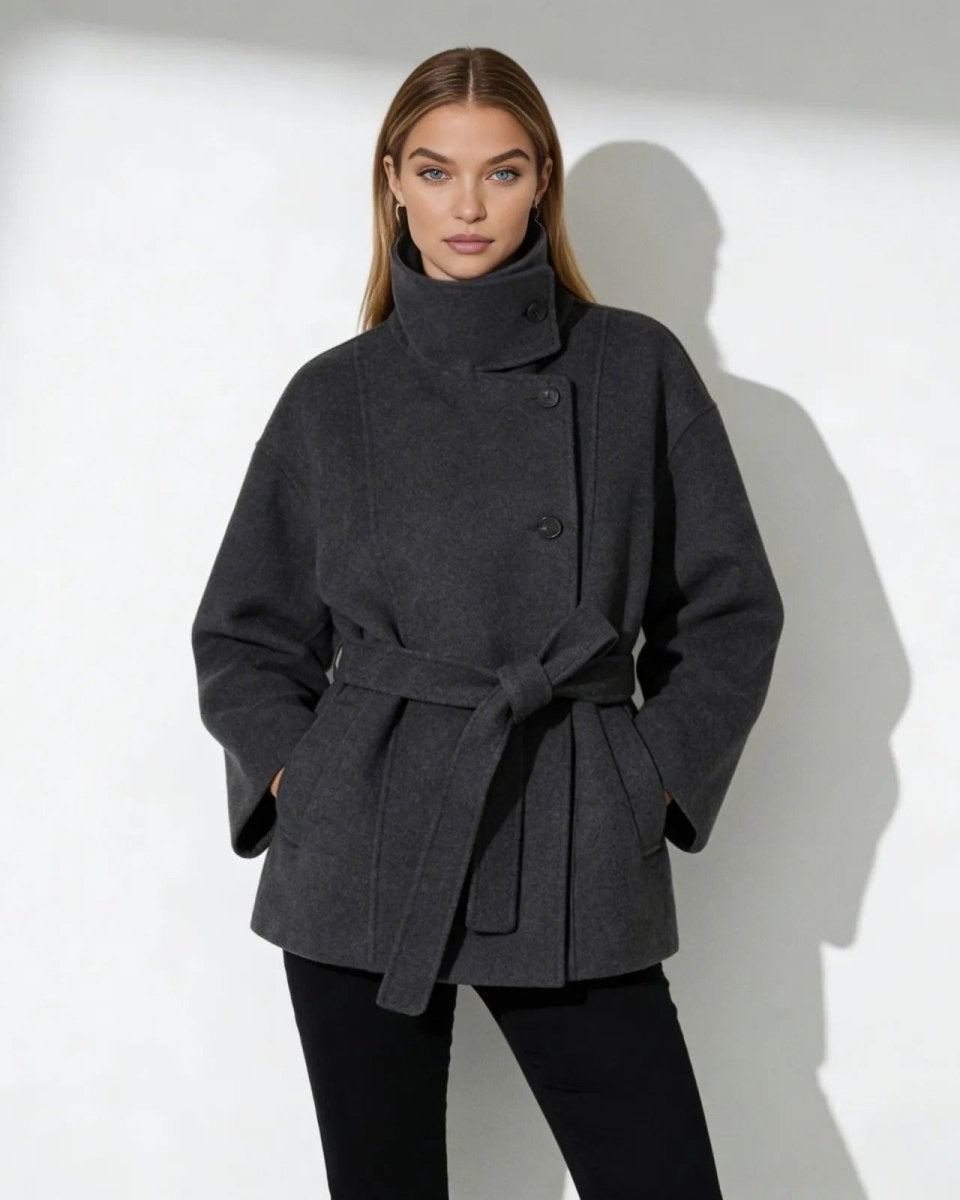 Model wearing the Verna short belted funnel neck wool coat in dark grey, tied at the waist.