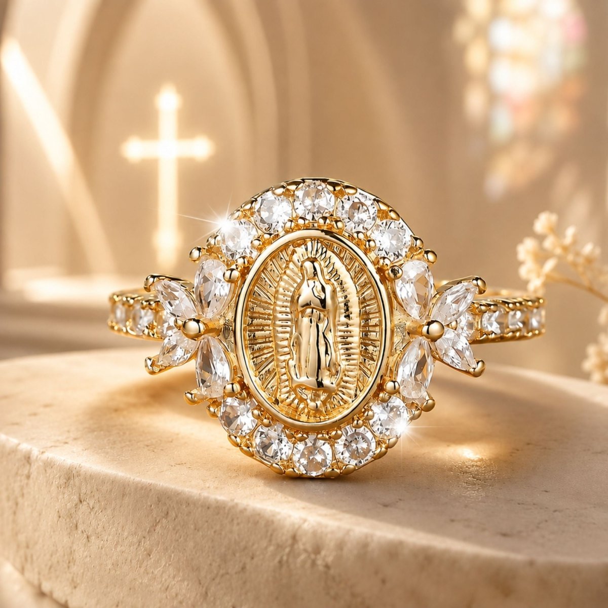 A gold-toned religious ring featuring a central oval medallion of the Virgin Mary, surrounded by clear gemstones and leaf-shaped side stones, displayed on a stone surface with a softly blurred church interior and cross in the background.