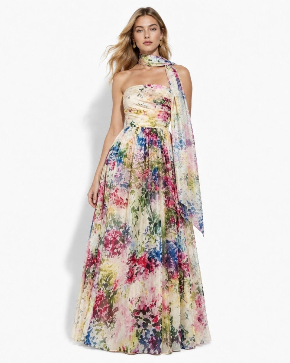Front view of a woman wearing the luxury watercolor floral chiffon maxi gown featuring a ruched strapless bodice and attached neck scarf.