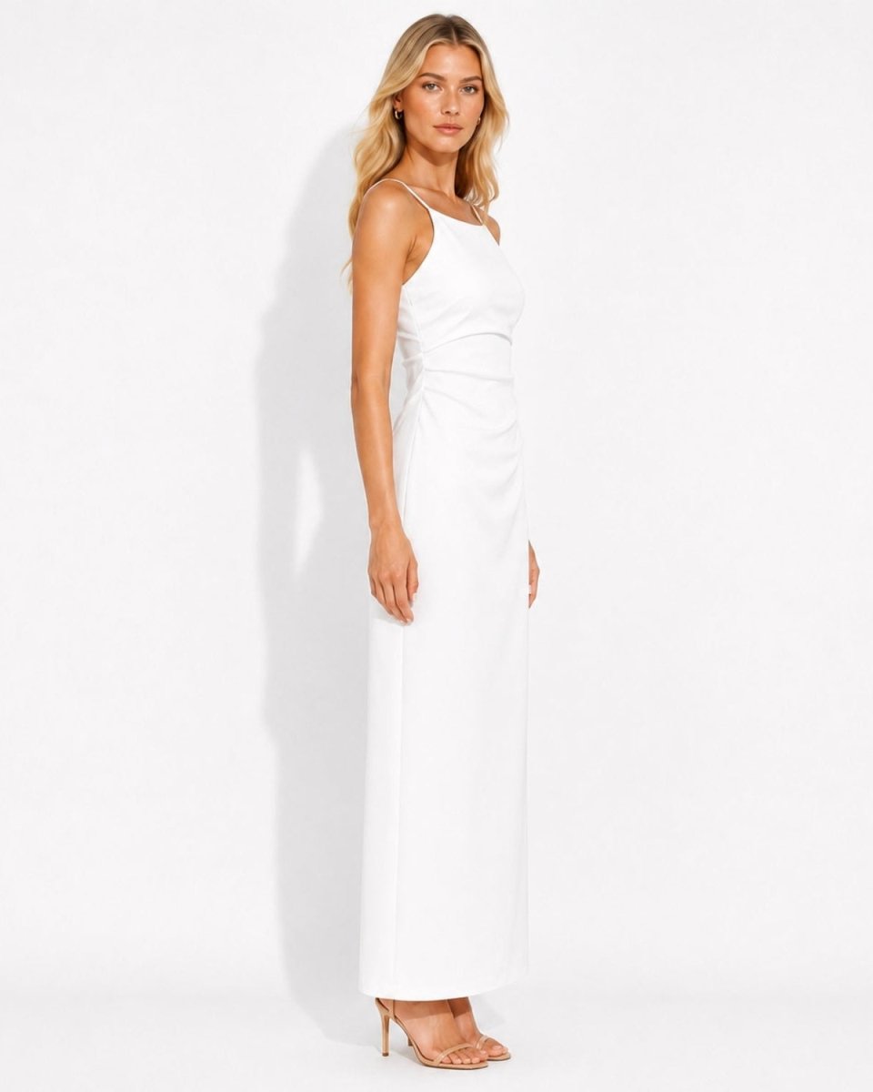A woman modeling a sleeveless white maxi dress with a draped neckline and gathered waist, standing against a plain white studio background.