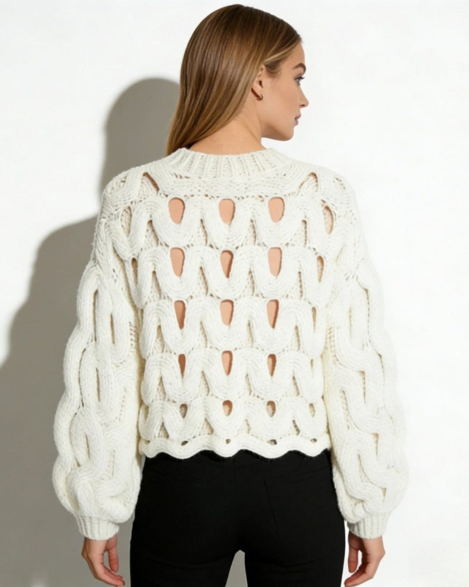 Back view of the white cutout chunky knit sweater, showing the full pattern and cropped, scalloped hem.