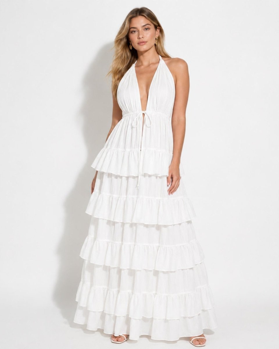 Front view of a woman modeling a white deep V-neck halter tiered maxi dress with a flowing silhouette.