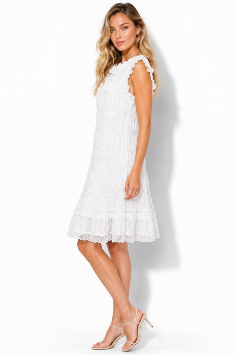 Side profile of Kouvr white ruffle mini dress styled with nude heels for resort wear