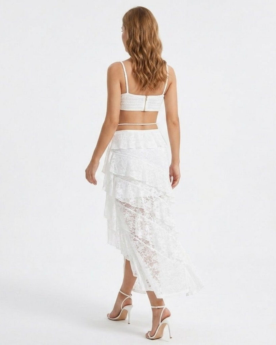 Back view of the white two piece outfit featuring an exposed top zipper and a flowing high-low lace skirt.