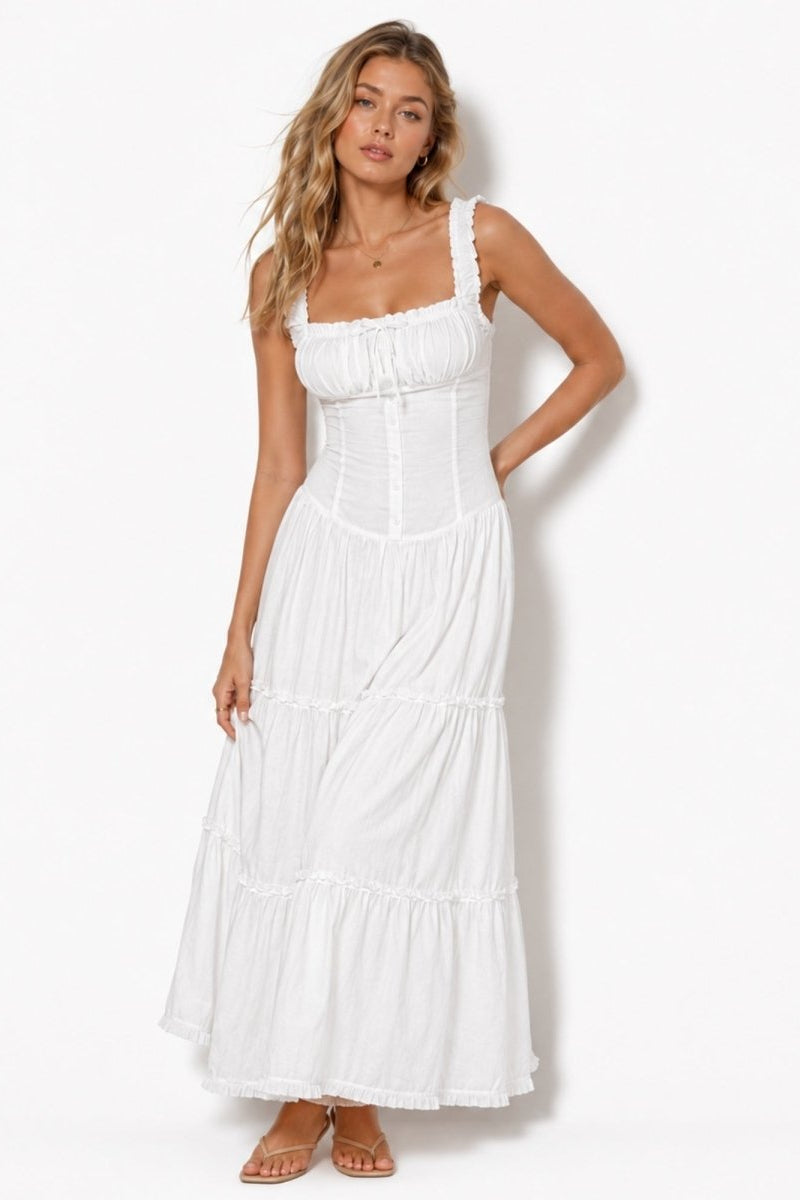 Full length front view of a model wearing a white luxury vacation maxi dress with tiered ruffle skirt and elegant square neckline.
