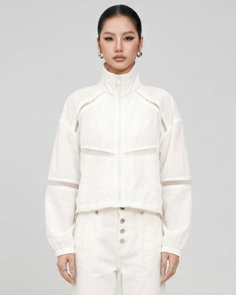 Front view of a woman wearing the Kouvr white mesh panel cropped track jacket and white pants