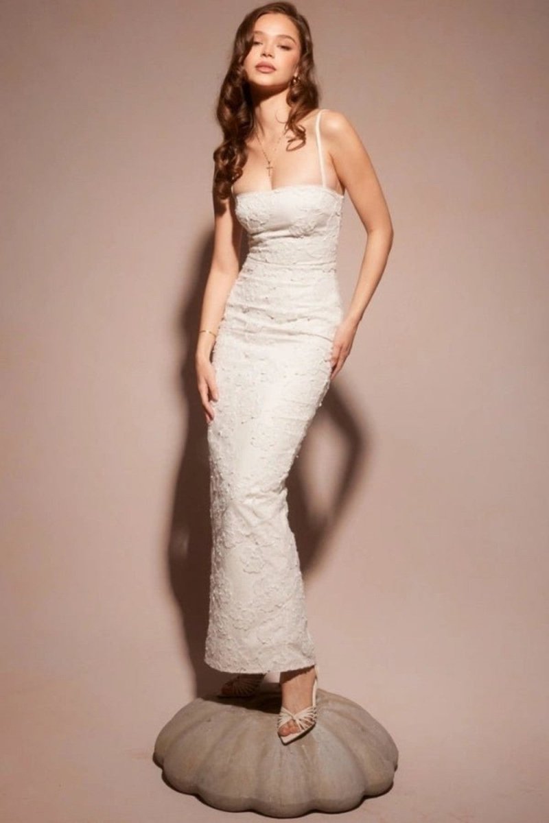 Woman wearing a white lace dress on a beige background