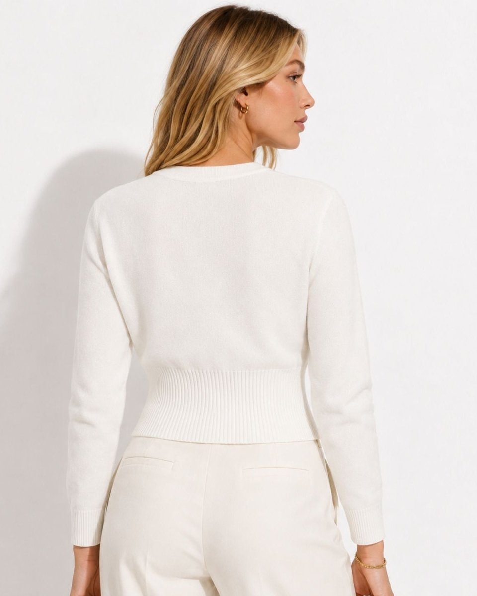 A woman shown from the back wearing a cream knit sweater and matching cream pants against a plain white studio background.