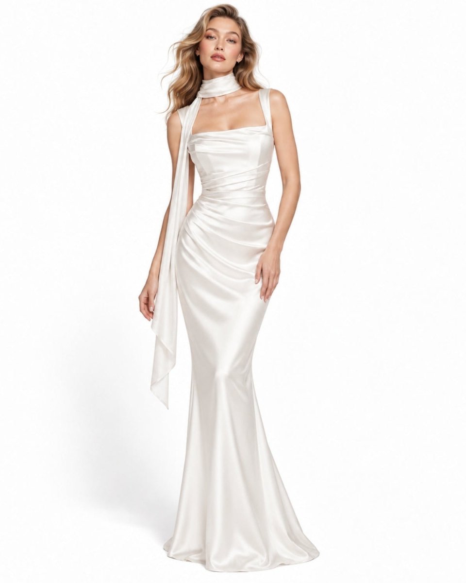 A woman modeling a floor-length white satin gown with a high halter neckline, draped side detail, and a fitted mermaid silhouette on a clean white studio background.