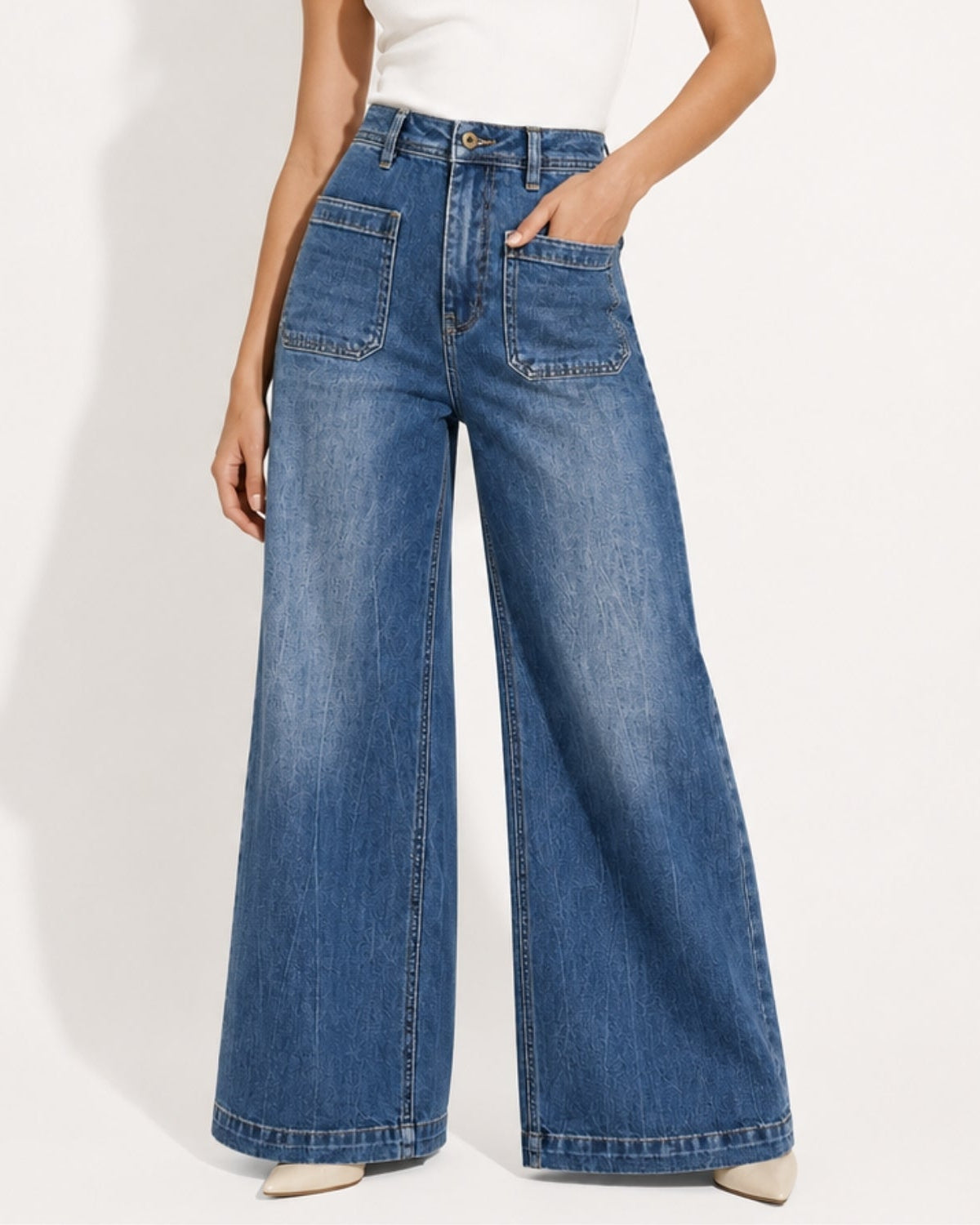 Close up detail of high-waisted denim trousers showing large front utilitarian patch pockets, center leg seam, and medium blue vintage wash.