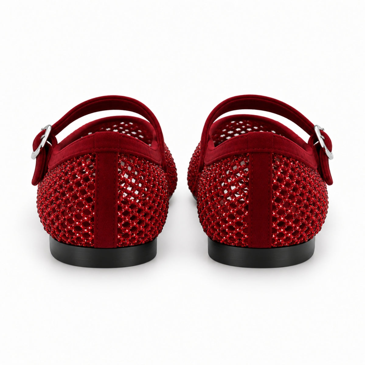 A pair of red flat shoes viewed from the back, featuring textured red mesh uppers with silver buckle straps and black soles, set against a plain white background.