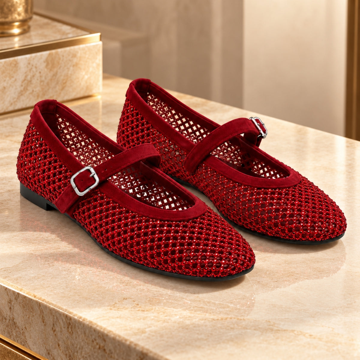 A pair of red open-knit Mary Jane flats with velvet straps and silver buckle details, displayed on a beige marble surface.