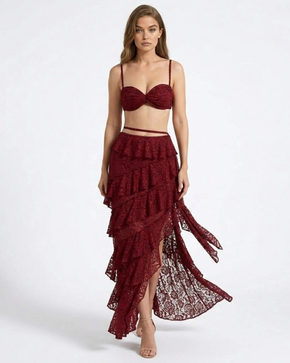 Woman walking wearing a wine red  lace two piece set featuring a sweetheart bustier crop top and an asymmetrical tiered ruffle maxi skirt by Fenlo Form.