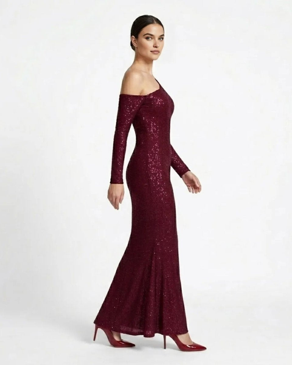 Side profile of a woman modeling an elegant wine red sparkly evening gown with asymmetric neckline. 