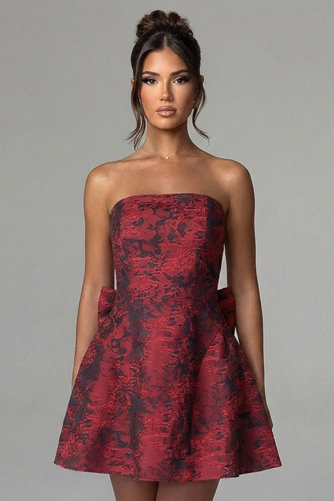 Close up view of the structured bodice and rich tactile floral jacquard fabric on a red strapless party dress.
