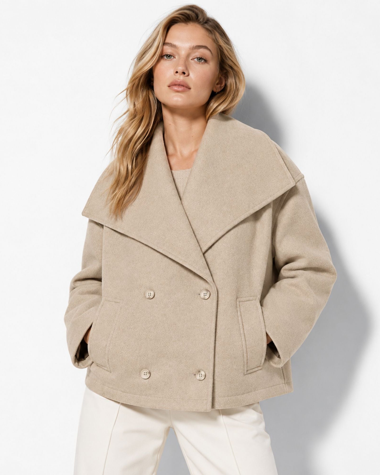 Woman modeling beige cropped wool peacoat with oversized statement collar and elegant double-breasted buttons.