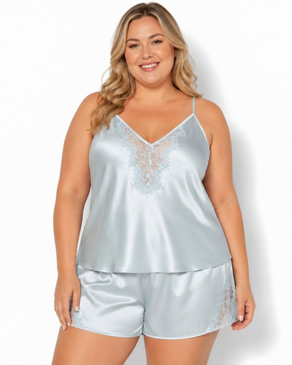 A woman modeling a light blue satin two-piece pajama set with matching lace trim, consisting of a camisole top and matching shorts, against a plain white background.