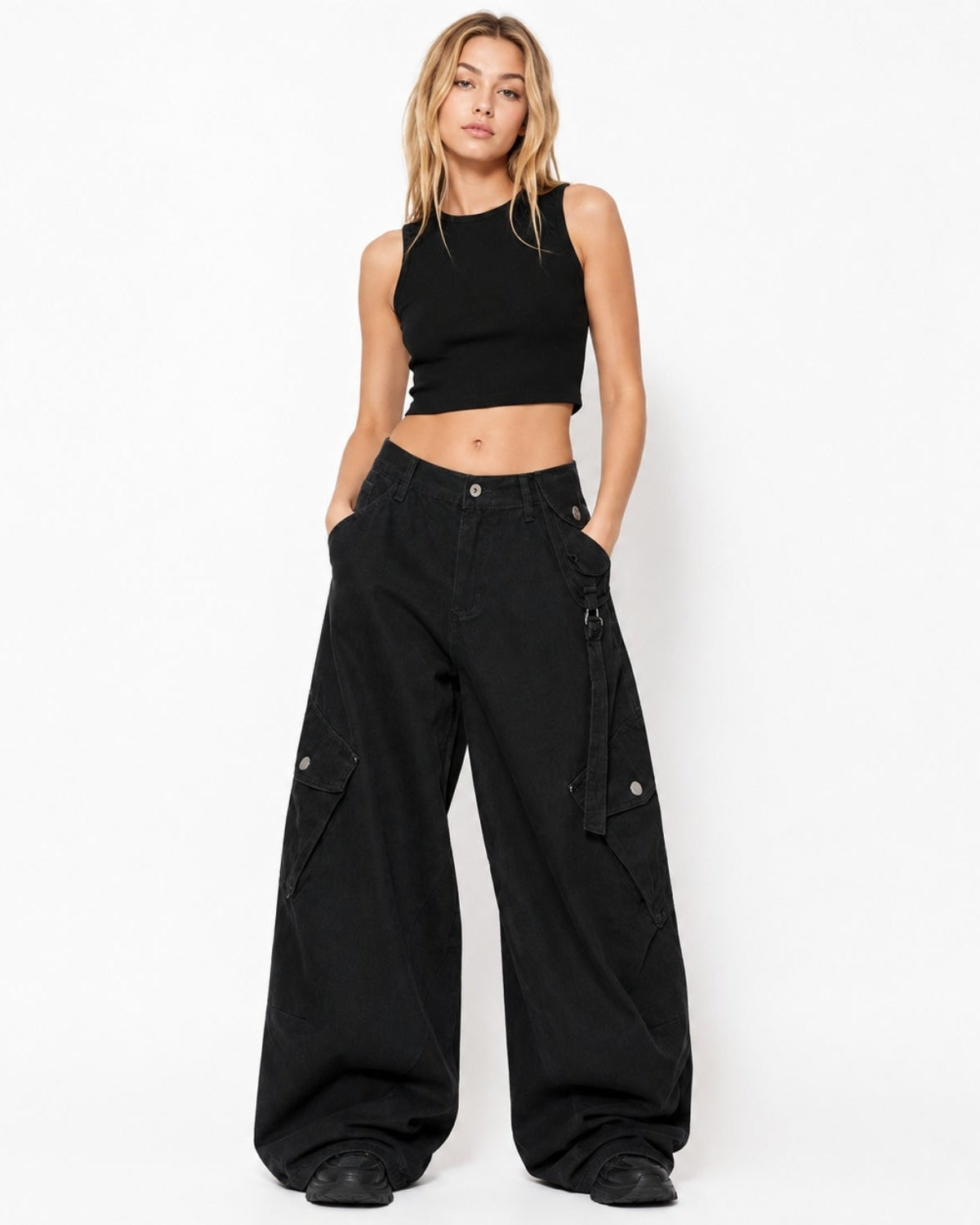 A woman modeling a black sleeveless crop top and black wide-leg cargo pants against a plain white studio background.