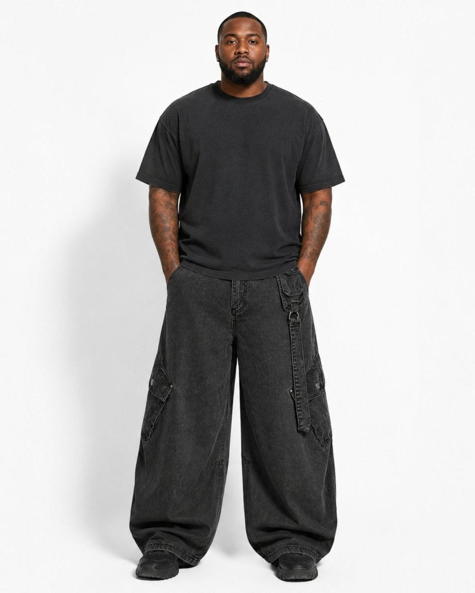 A man modeling a black crewneck t-shirt and wide-leg black cargo pants against a plain white studio background.