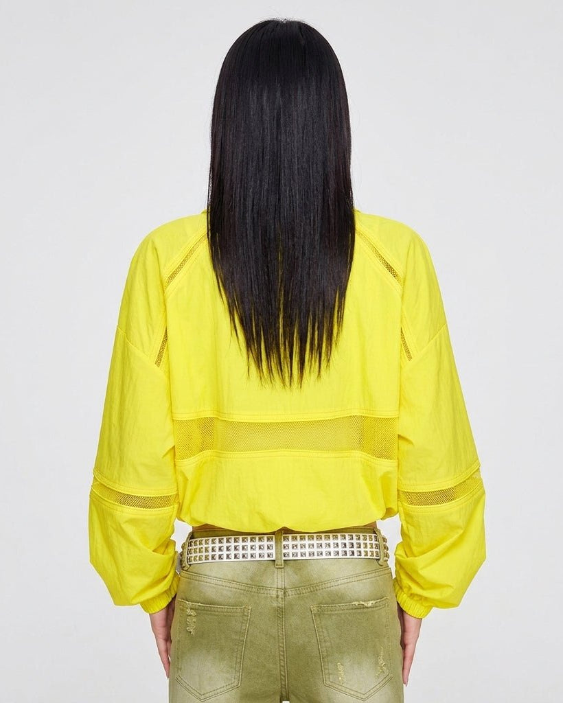 Back view of women's yellow athleisure zip-up jacket showing horizontal mesh inset details and elastic hem.