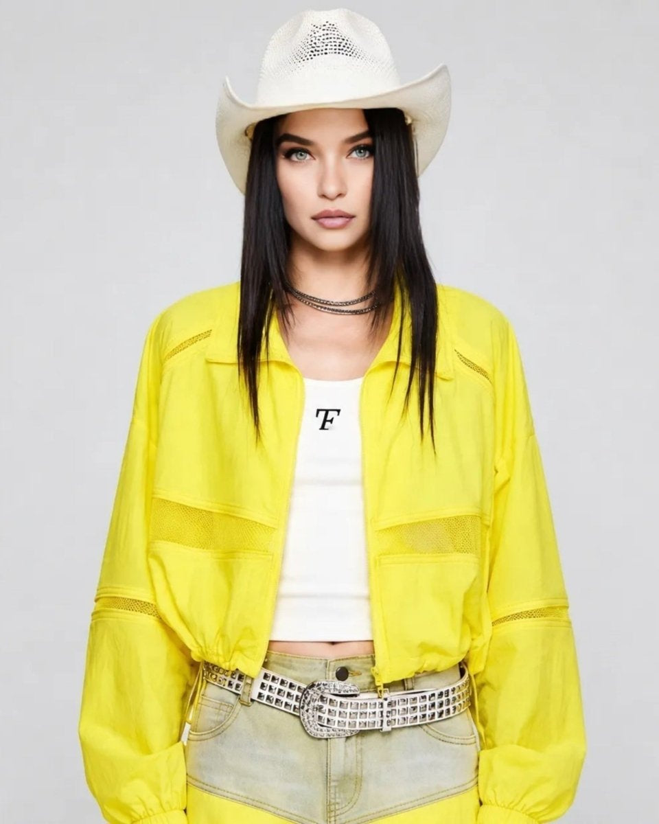 Woman wearing Kouvr yellow cropped lightweight windbreaker jacket with sheer mesh panels and western hat.