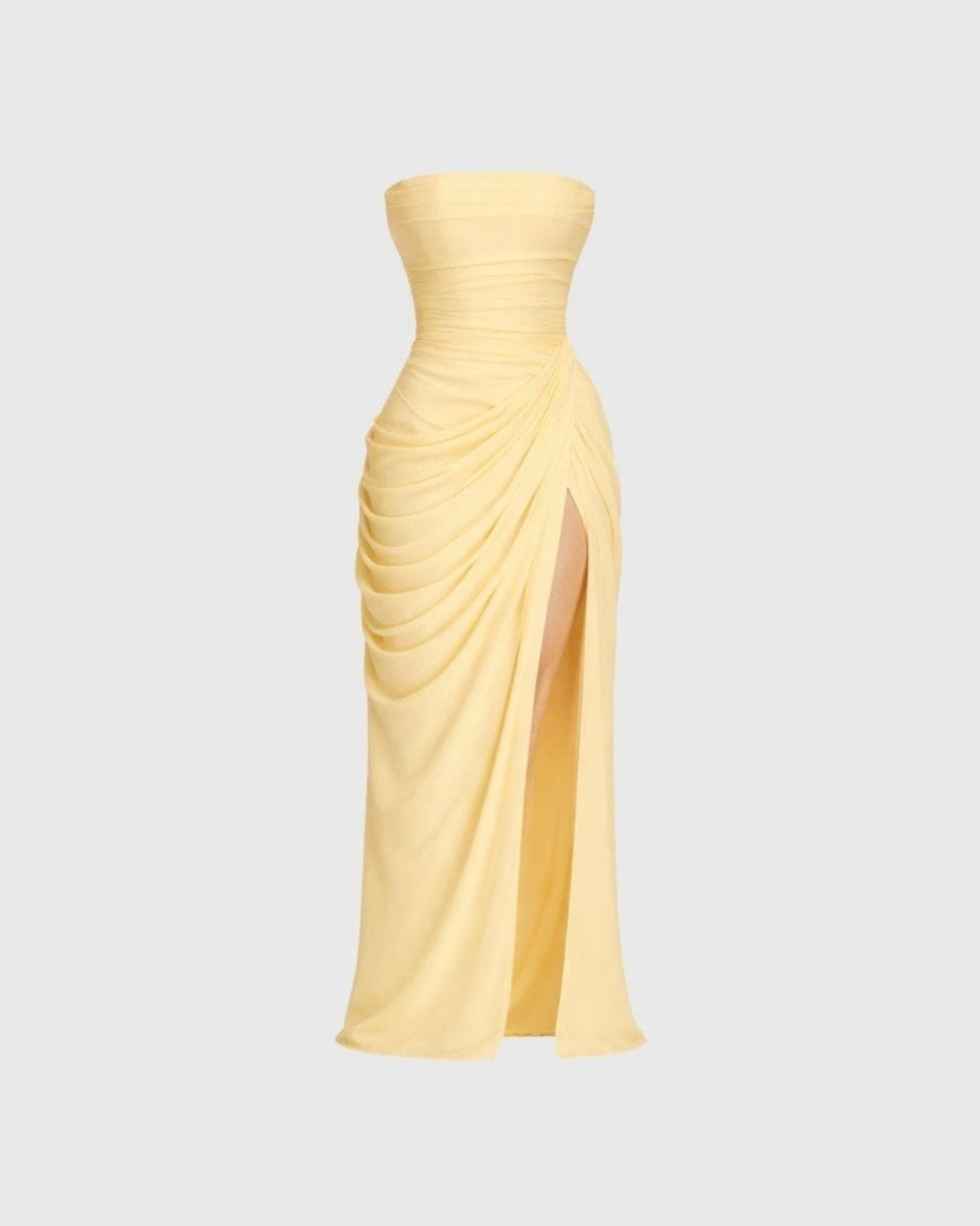 Front flat lay studio view of pale yellow strapless gown with draped waist and thigh slit detail.